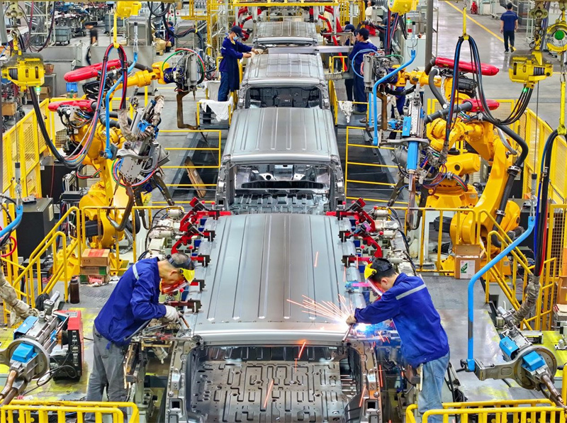 Dans l'atelier d'emboutissage et de soudage d'un fabricant de véhicules commerciaux à énergie nouvelle situé dans la zone de développement économique et technologique de la ville de Ganzhou, dans la province du Jiangxi (est de la Chine), les robots industriels fonctionnent rapidement et les soudeurs soudent et assemblent des véhicules de transport express électriques à énergies nouvelles. (Zhu Haipeng / Pic.people.com.cn)