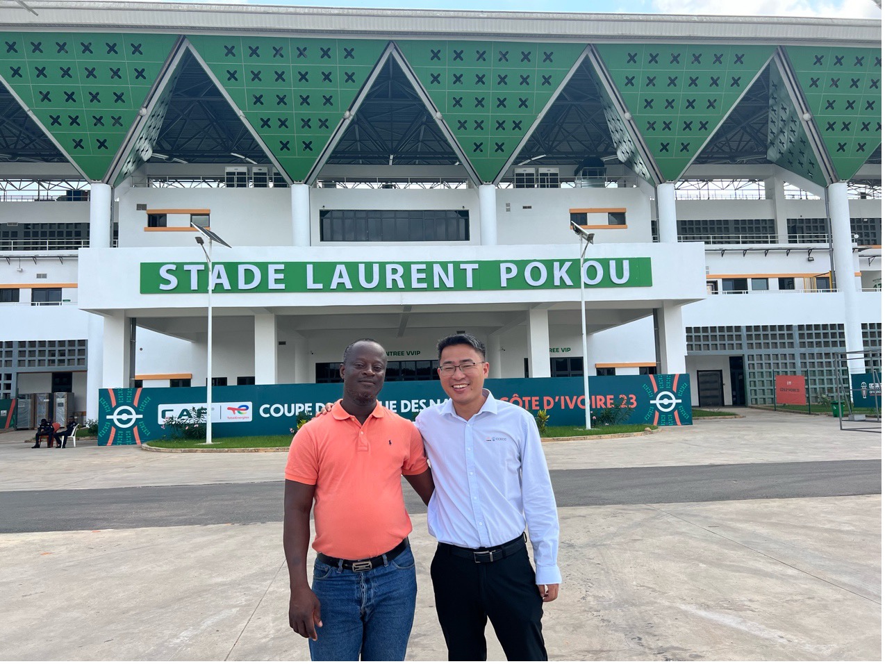 Koffi Lopez, représentant régional de l'Office national des sports à San-Pedro, aux côtés de son collègue chinois Shi Yongsheng, chef de projet du stade de San Pedro construit par CCECC, devant le stade Laurent Pokou, à San-Pédro, en Côte d'Ivoire. (Photo / le Quotidien du Peuple en ligne)