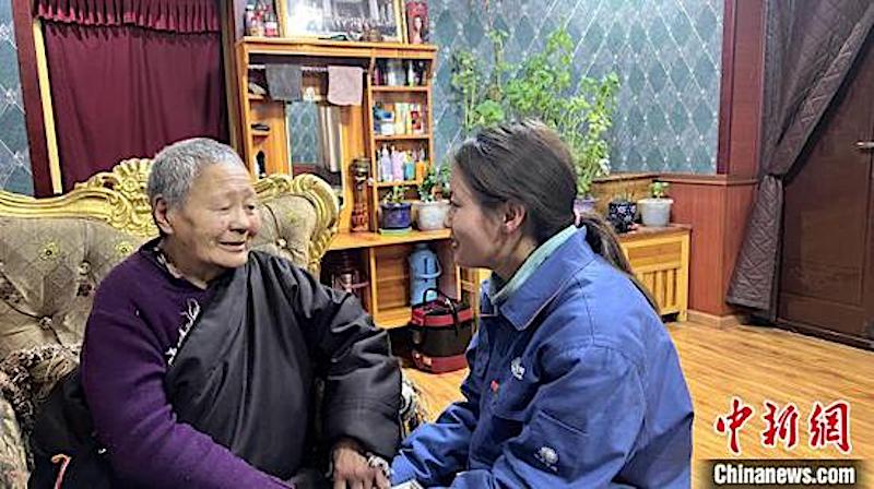 Zaxi Lamao (à droite) explique à une personne âgée les précautions à prendre concernant l'électricité. (Photo / China News Service)