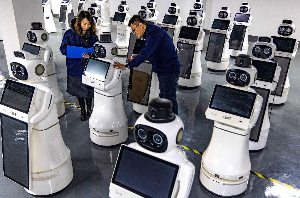 Des techniciens déboguent des robots de réception dans un atelier d'une entreprise technologique à Zhangye, dans la province du Gansu (nord-ouest de la Chine). (Yang Xiao / Pic.people.com.cn)