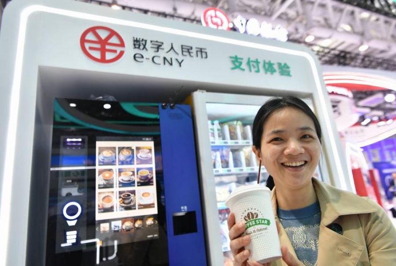 Une visiteuse présente un verre de café acheté en yuan numérique, ou e-CNY, lors d