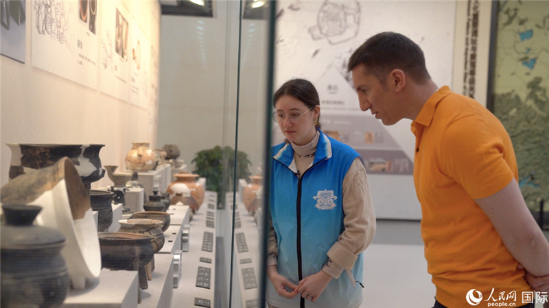 Emma Chen (à gauche), tutrice bénévole bilingue au Musée Liangzhu de Hangzhou, capitale de la province du Zhejiang (est de la Chine), explique un objet exposé à un visiteur étranger. (Yuan Meng / Le Quotidien du Peuple en ligne)
