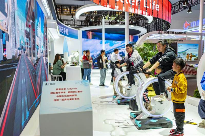 Des visiteurs essaient des vélos numériques sur le stand de Sinopec lors de l'événement China Brand Day, le 12 mai 2024 à Shanghai (est de la Chine). (Wang Chu / Pic.people.com.cn)