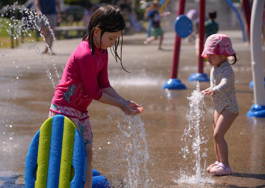 Des enfants se rafraîchissent dans un parc à jets d