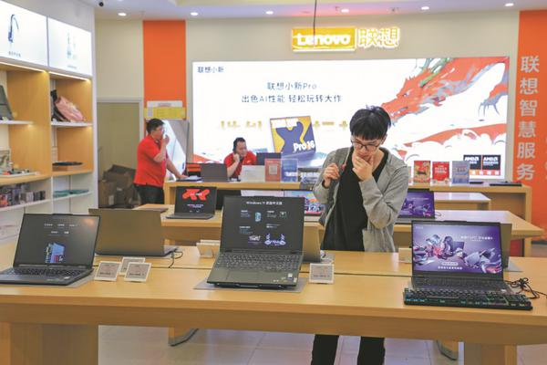 Un consommateur regarde des ordinateurs portables Lenovo à Shanghai en mai. (Photo / China Daily)