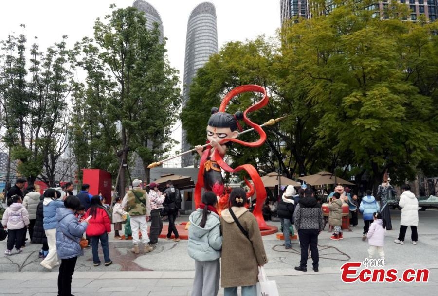 Des touristes posent pour des photos avec une sculpture de « Ne Zha » à Chengdu, capitale de la province du Sichuan (sud-ouest de la Chine), le 6 février 2025. (An Yuan / China News Service)