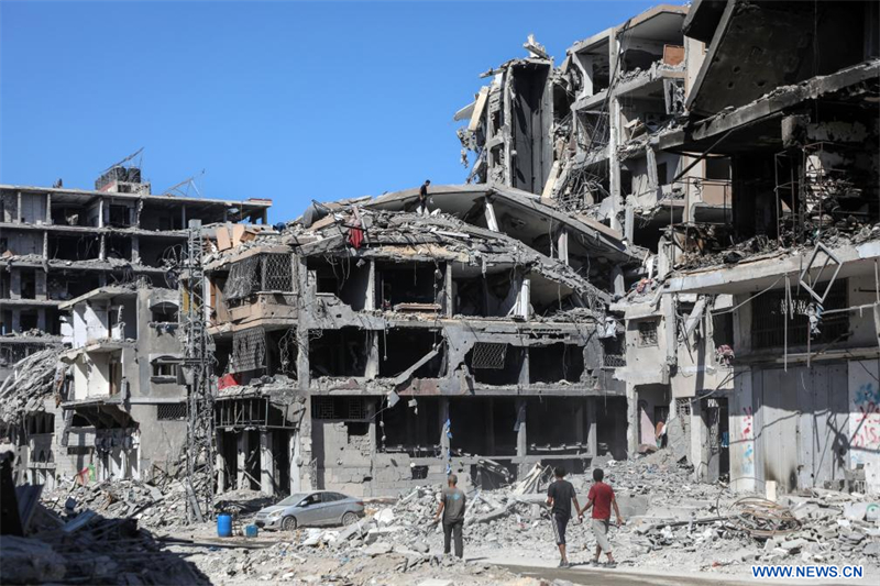 Des personnes sont vues dans une rue bordée de bâtiments détruits à Gaza, le 19 octobre 2025. Les Forces de défense israéliennes (FDI) ont indiqué dimanche dans un communiqué avoir lancé une nouvelle vague de frappes contre des cibles du Hamas dans le sud de la bande de Gaza. (Xinhua/Rizek Abdeljawad)