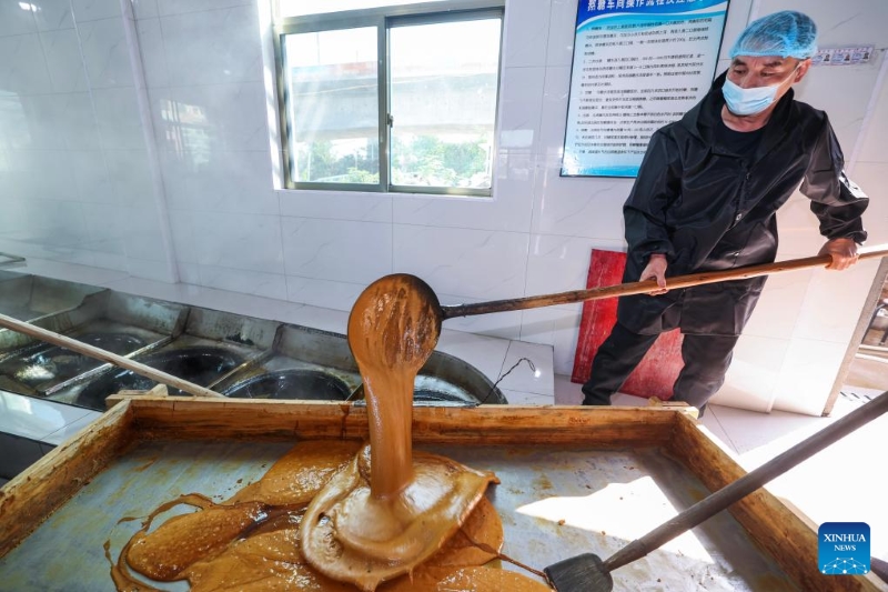Un ouvrier d'une usine sucrière transvase du sirop de sucre roux dans le village de Shangyang de la ville d'Yiwu, dans la province du Zhejiang (est de la Chine), le 15 novembre 2025. (Xinhua/Xu Yu)