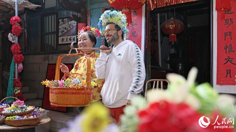 Un influenceur de voyage européen portant un couvre-chef fleuri pose pour une photo avec une femme locale dans le village de Xunpu, à Quanzhou, dans la province du Fujian (sud-est de la Chine). (Li Changqian / Le Quotidien du Peuple en ligne)