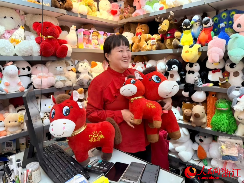 Zhang Huoqing, propriétaire de magasin, expose des chevaux jouets au visage en pleurs sur le marché du commerce international d’Yiwu, dans la province du Zhejiang (est de la Chine). (Cheng Xin / Le Quotidien du Peuple en ligne)