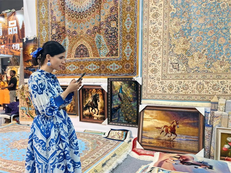 Un membre du personnel présente des produits via diffusion en direct sur le stand de l'Iran lors de la 10e Exposition internationale de la Route de la Soie à Xi'an, capitale de la province du Shaanxi (nord-ouest de la Chine), le 21 mai 2026. (Zhang Sijie/Xinhua)