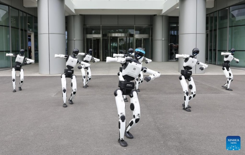 Des robots humanoïdes accueillent les visiteurs avec une danse devant la base de données et de formation des robots à intelligence intégrée du Centre d'innovation en robotique humanoïde de Beijing, le 12 juin 2026. (Xinhua/Wang Jingqiang)