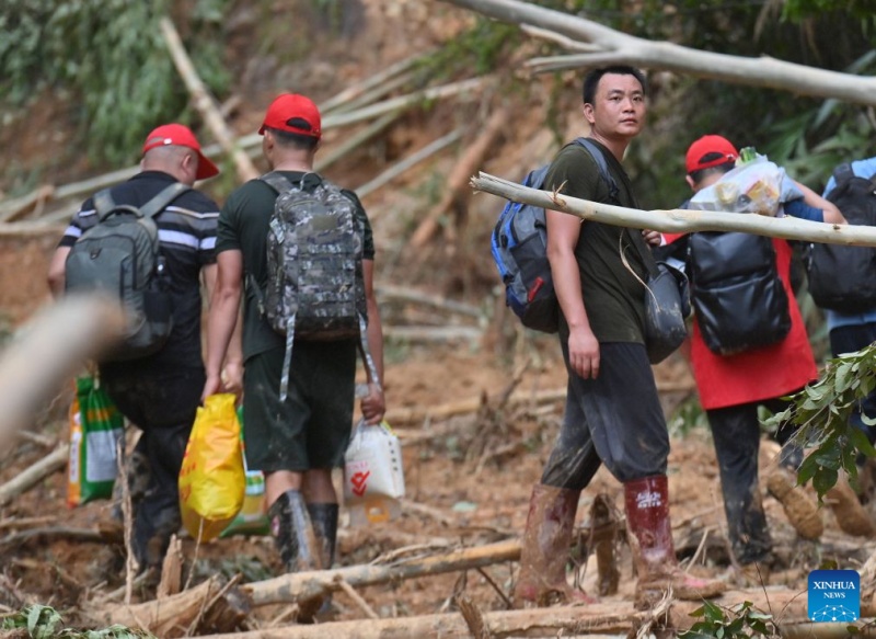 Li Henghao (3e à gauche) regarde des gens traverser une section effondrée d'une route dans le canton de Zhenlong de la ville de Hengzhou, à Nanning, capitale de la région autonome Zhuang du Guangxi (sud de la Chine), le 10 juillet 2026. (Xinhua/Huang Xiaobang)