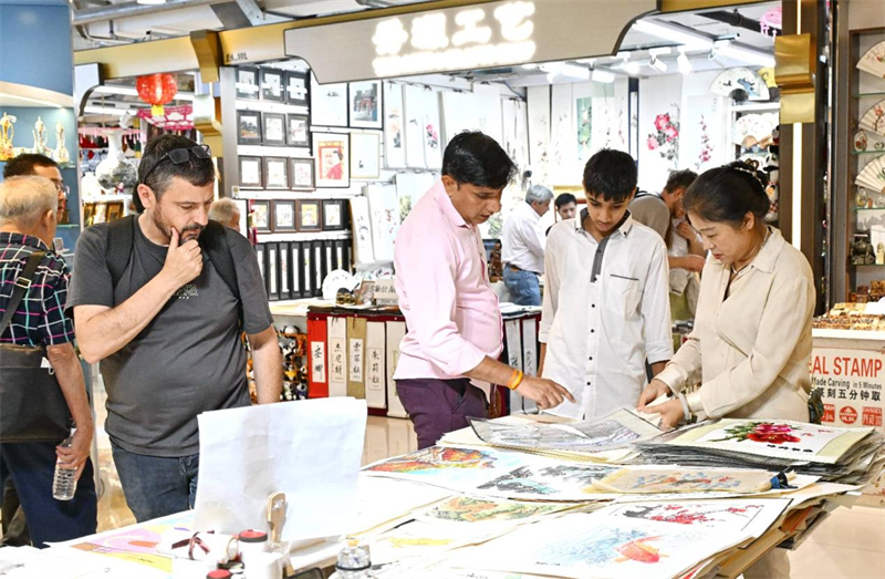 Des touristes étrangers achètent des produits culturels et artistiques au centre commercial de la Rue de la Soie de Beijing. (Photo/Hu Qingming)