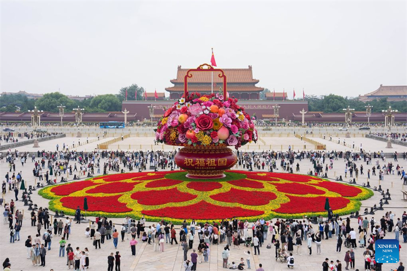 Des touristes admirent une corbeille de fleurs géante installée sur la place Tian'anmen, le 25 septembre 2026 à Beijing. (Ju Huanzong/Xinhua)