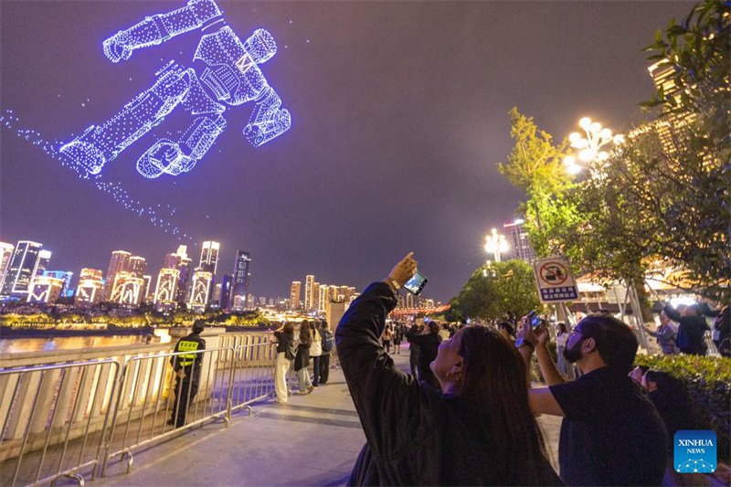 Des touristes étrangers prennent des photos d'un spectacle de lumière de drones rue Nanbin, dans le district de Nan'an de la municipalité de Chongqing (sud-ouest de la Chine), le 22 avril. (Huang Wei/Xinhua)