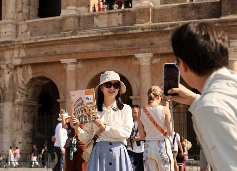 Un touriste chinois pose pour une photo le 4 octobre devant le Colisée à Rome en tenant un manuel d’histoire pour lycéens chinois dont la couverture représente le monument. Rome a accueilli un grand nombre de touristes chinois durant les récentes vacances de la Fête nationale. (Li Jing/Xinhua)